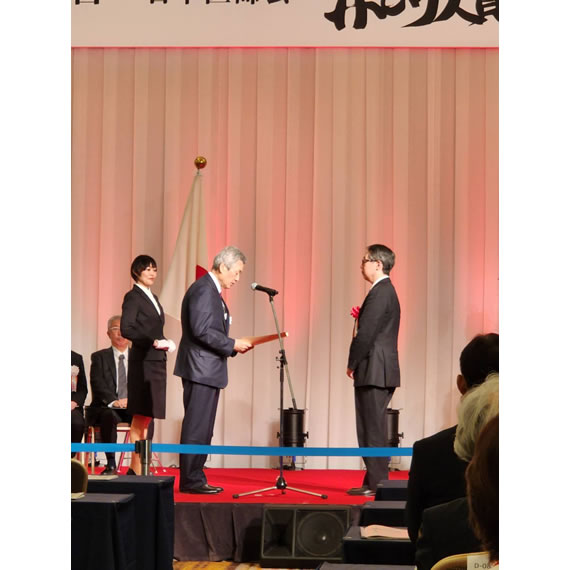 日本医師会長から表彰状を受け取った場面